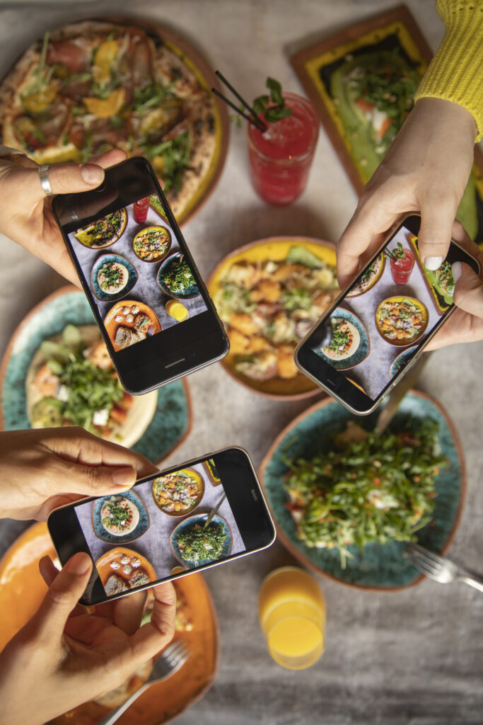 Amigos haciendo fotografías a comida en un restaurante para subirlas a Instagram y compartir su experiencia.