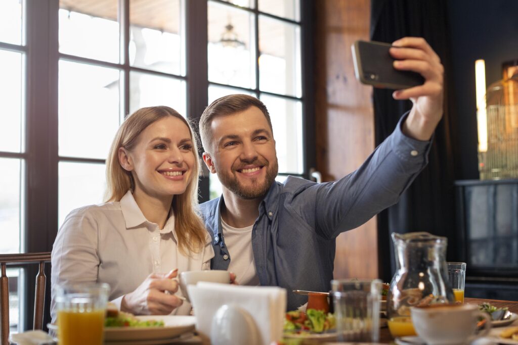 Una pareja joven sonríe feliz mientras se hace un selfie en un restaurante de su gusto.