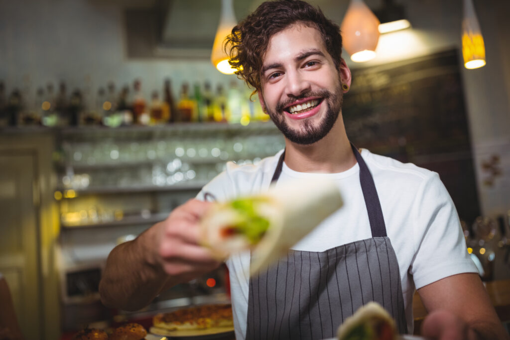 Cocinero sonriente ofreciendo un bocado.