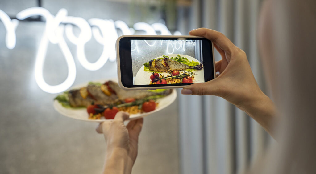 Community manager freelance haciendo fotos con el móvil para tu restaurante.