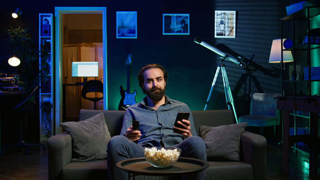 Hombre viendo la tele mientras consulta su smartphone.