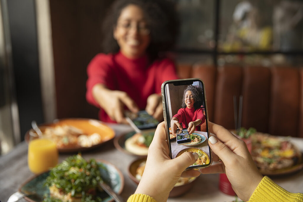 Mujer haciendo una foto en un restaurante para subirla a Instagram y conseguir likes.