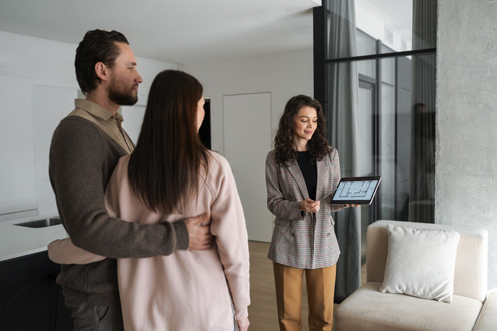 Mujer mostrando el plano de una vivienda a una pareja interesada en comprar.